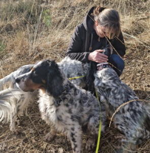 Elaine zit gehurkt met drie van haar honden