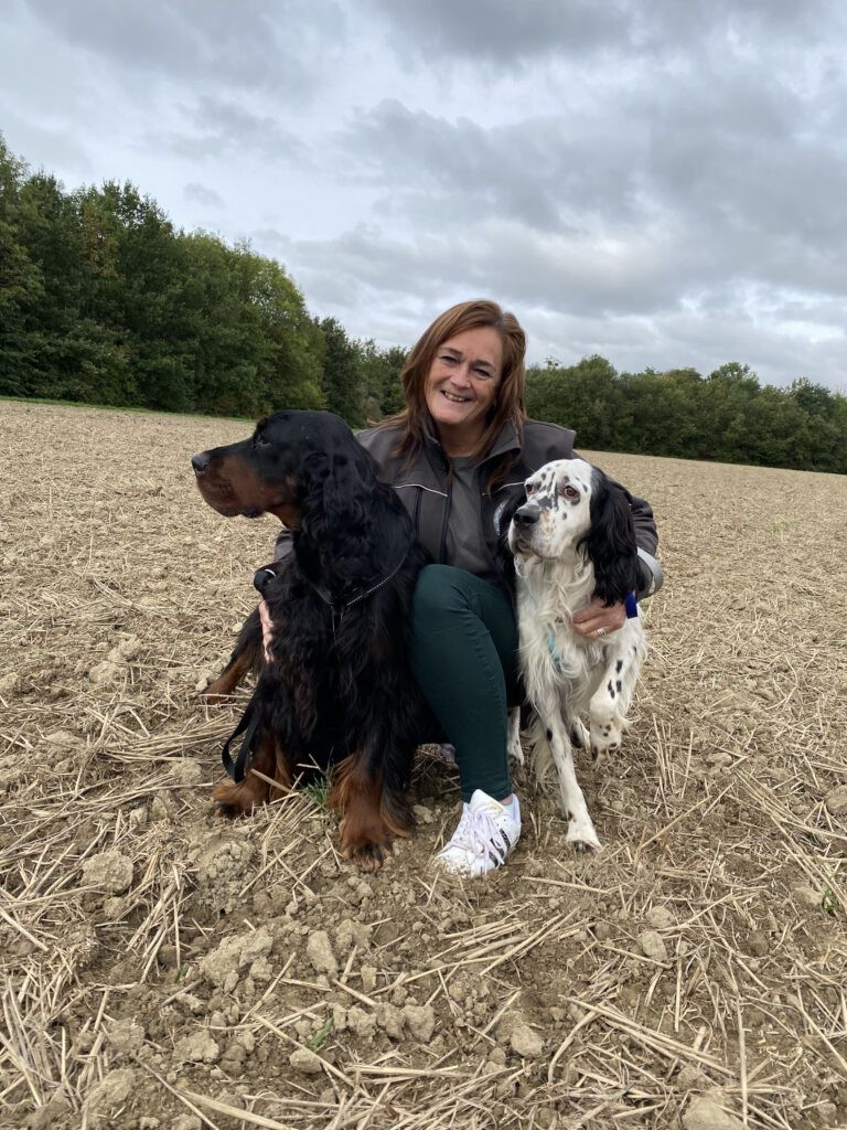 Elaine staat met twee honden op een leeg veld